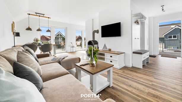 Uma sala de estar moderna com um sofá, uma mesa de centro e uma TV fixada na parede.