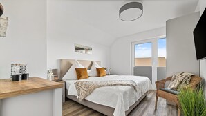 Quarto com cama, mesa de cabeceira e uma cadeira.