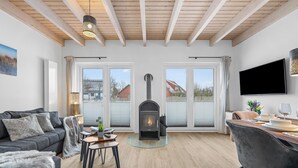 Una sala de estar con chimenea, un sofá, una mesa de comedor con sillas y un televisor montado en la pared.