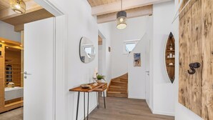 Un pasillo con escalera de madera, un espejo, una pequeña mesa con una vela y un panel de pared de madera.
