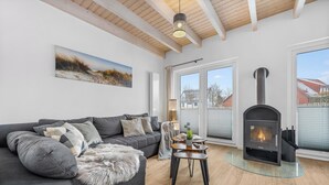 Una sala de estar moderna con un sofá, una mesa de centro de vidrio, una chimenea y un ventanal grande.