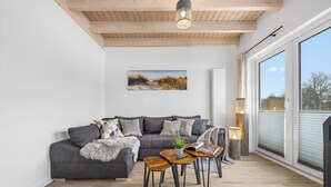 Una sala moderna con un sofá gris, una mesa de centro y un ventanal grande.