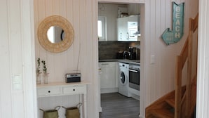 A compact kitchen with a washing machine, a coffee maker, and a wooden staircase leading to a loft. - Meerhaus - Detached House, Infrared Sauna, Fireplace, Bathtub, Terrace (Olpenitz)