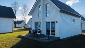 A single-story house with a front porch and a dining area. - Meerhaus - Detached House, Infrared Sauna, Fireplace, Bathtub, Terrace (Olpenitz)