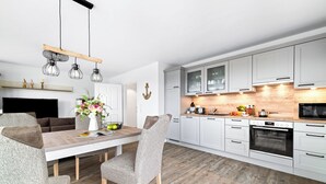 Una cucina moderna con mobili bianchi, un piano di lavoro in legno e un forno integrato.