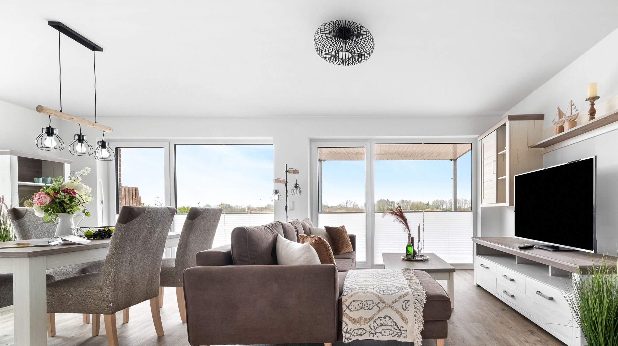 En moderne stue med sofa, stole, spisebord og fjernsyn.