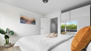 Una camera da letto con un letto, una pianta in vaso, un quadro e una finestra vista panoramica.