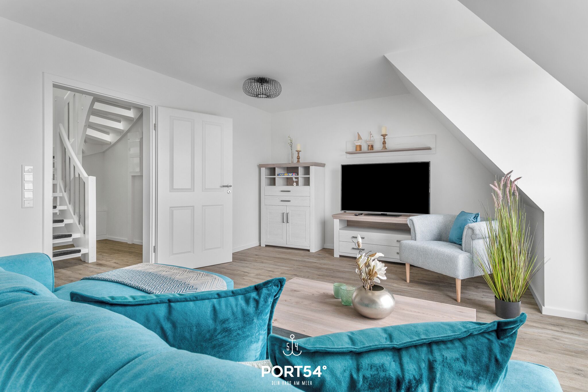 Ein modernes Wohnzimmer mit Treppe, Flachbildfernseher und einer gemütlichen Couch.