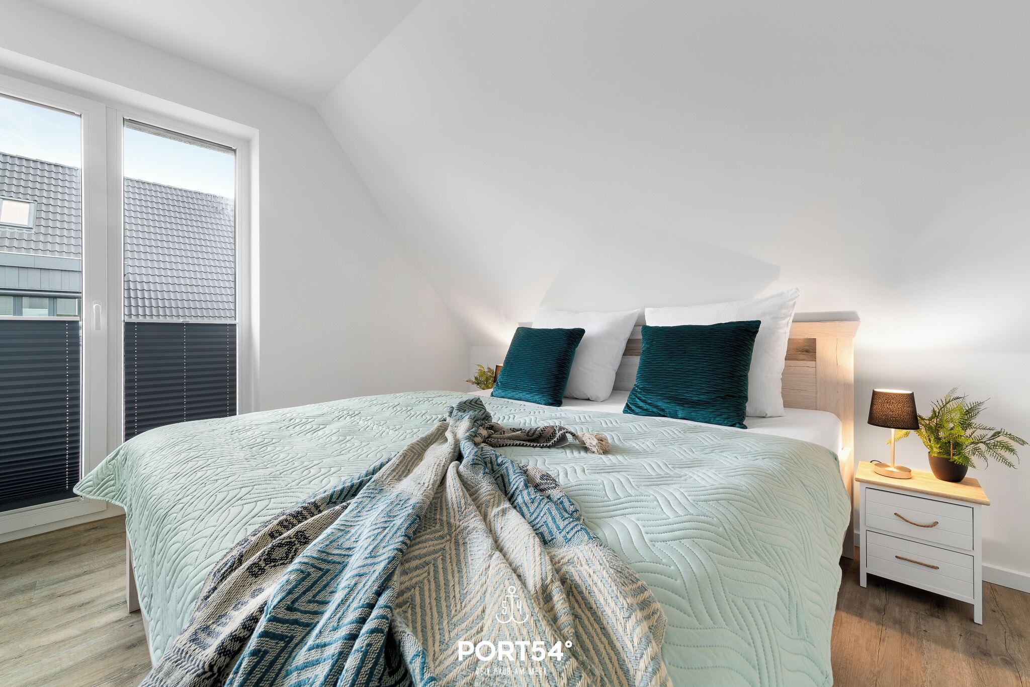 Une chambre à coucher avec un lit, une table de chevet, une lampe et une fenêtre.