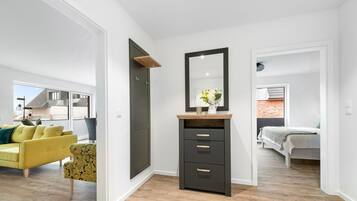 A modern bedroom with a large mirror, a bedside table with a vase, and a bed.