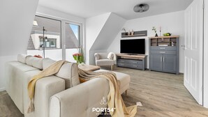 Un salon moderne avec un canapé, un téléviseur et des meubles de rangement gris.