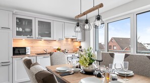 Een moderne keuken met witte kasten, een houten aanrecht en een eethoek met een tafel gedekt voor twee personen.