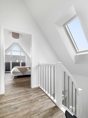 Ein modernes Schlafzimmer im Loft-Stil mit Schräge, Dachfenster und Blick auf das Dach.