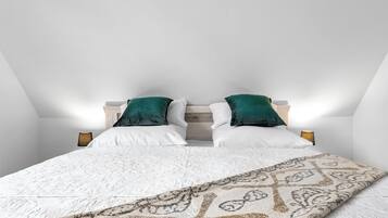 A bedroom with a bed, two pillows, a patterned throw, and bedside lamps.