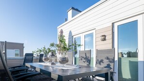 Una terraza en la azotea con una mesa de comedor, sillas y objetos decorativos.