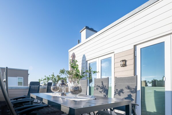 Une terrasse sur le toit, aménagée avec une table à manger, des chaises et des éléments de décoration.