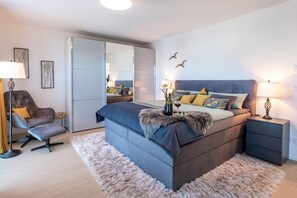 Une chambre moderne avec un grand lit, des tables de chevet, une chaise et une armoire.