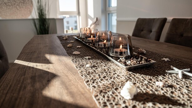 Una mesa de comedor de madera con un centro de velas, estrellas de mar y conchas marinas.