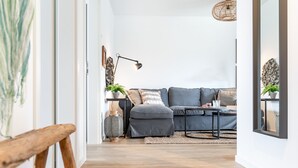 A modern living room with a grey sofa, a coffee table, and a wicker lamp. - Diek No. 2 in the North Sea resort - close to the beach and the North Sea, fireplace, terrace, pets (Büsum)