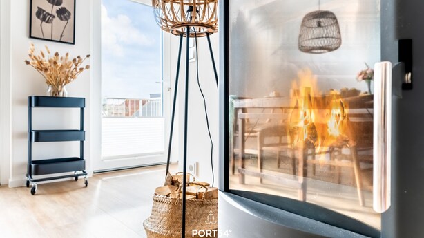 Ein modernes Wohnzimmer mit großem Fenster, Kamin und Blick ins Freie.