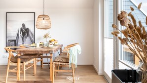 Ein Essbereich mit einem Holztisch, Stühlen, einer hängenden Korbschaukel-Lampe und einem gerahmten Bild an der Wand.