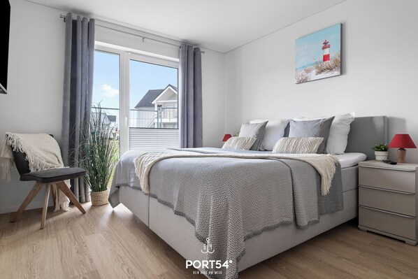 Une chambre à coucher moderne avec un grand lit, des rideaux gris, une plante en pot et une vue sur l’extérieur.