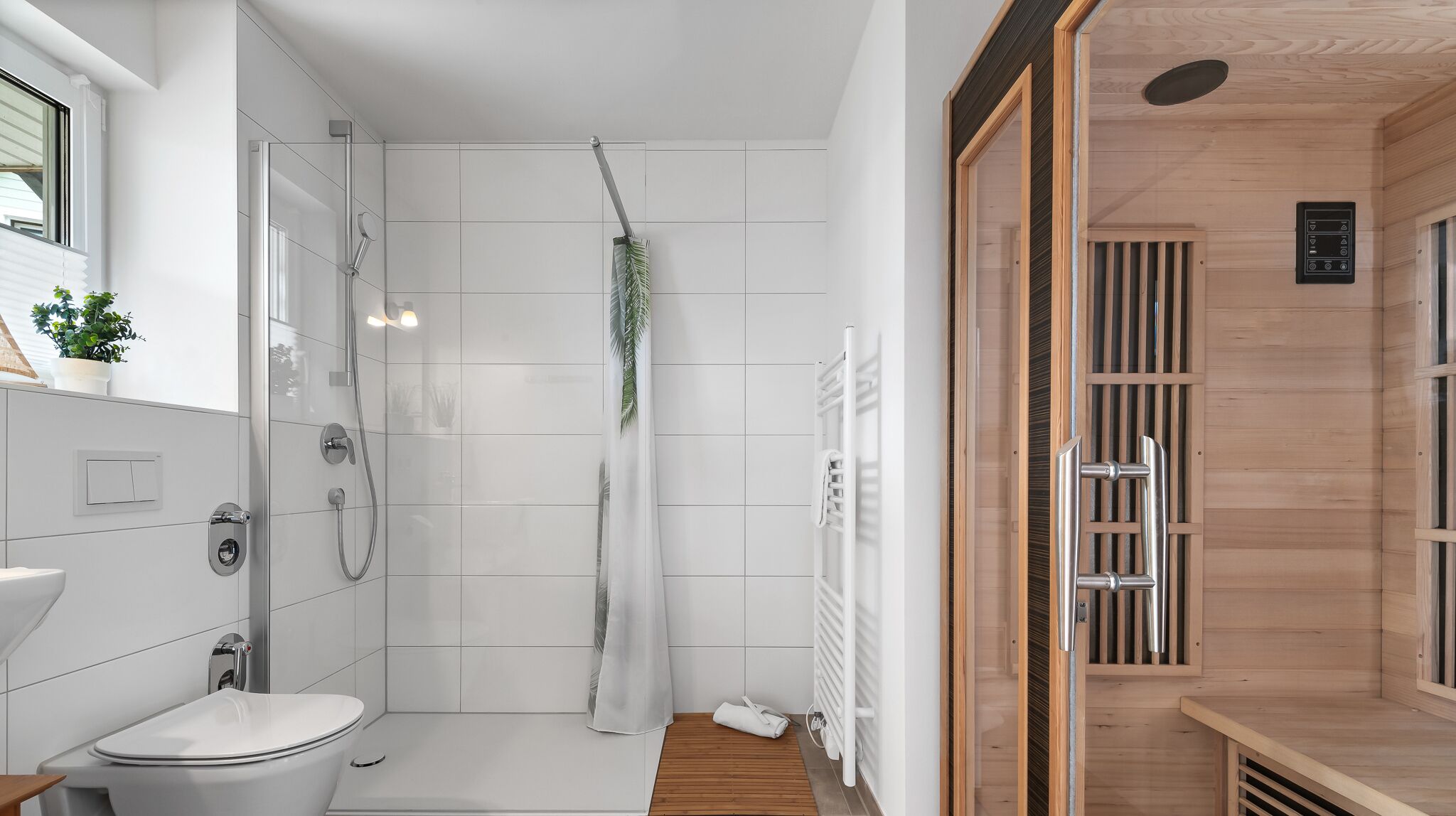 A modern bathroom with a shower, toilet, and a wooden sauna area.