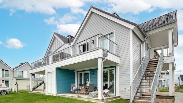 Une maison à deux étages avec un patio couvert, un escalier et un garage.
