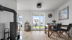 Un salon moderne avec une cheminée, un coin repas et une vue sur l’extérieur.