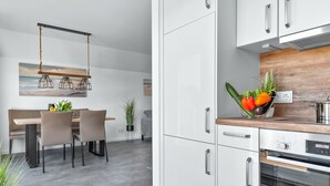 Une cuisine moderne avec des armoires blanches, un plan de travail en bois et un four encastré.