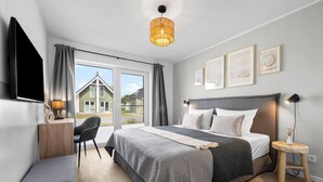 Ein modernes Schlafzimmer mit einem großen Bett, Nachttischen, einem Schreibtisch und einem Fernseher.
