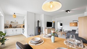 Eine moderne Küche mit weißen Schränken, einem eingebauten Herd und einem Essbereich mit einem Holztisch für zwei Personen.