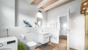 A modern bathroom with a washing machine, a sink, and a mirror. - Ferienhaus Meerglück (Büsum)