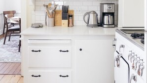 A kitchen with white cabinets, a stove, and a coffee maker.