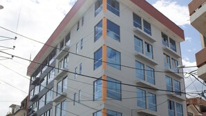 Un edificio de varios pisos con fachada plana, amplias ventanas y una combinación de colores rojo y blanco.