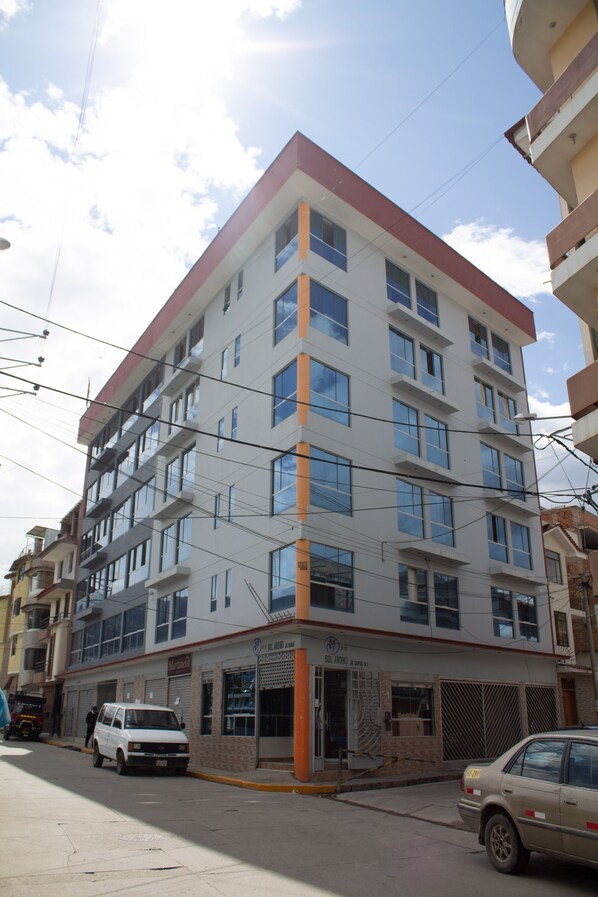 Un edificio de varios pisos con fachada plana, amplias ventanas y una combinación de colores rojo y blanco.