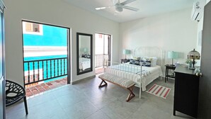 A bedroom with a bed, bedside tables, a ceiling fan, a window, and a view of the outside.