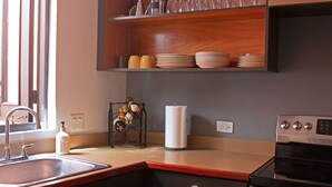 A kitchen with a sink, stove, and wooden shelves above the counter.