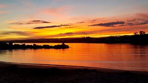 A sunset over a calm body of water with a silhouette of a rocky outcrop in the foreground. - Fantastic sea views! Close to the beach apartment (Estepona)