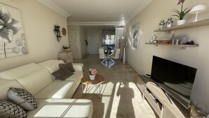 A modern living room with a sofa, coffee table, and TV. There is a kitchen in the background. - Fantastic sea views! Close to the beach apartment (Estepona)