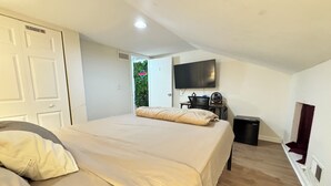 Un dormitorio con cama, escritorio, televisor y ventana.