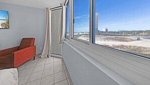 Ein Zimmer mit großem Fenster und Meerblick, ein roter Sessel und ein weißes Kissen.