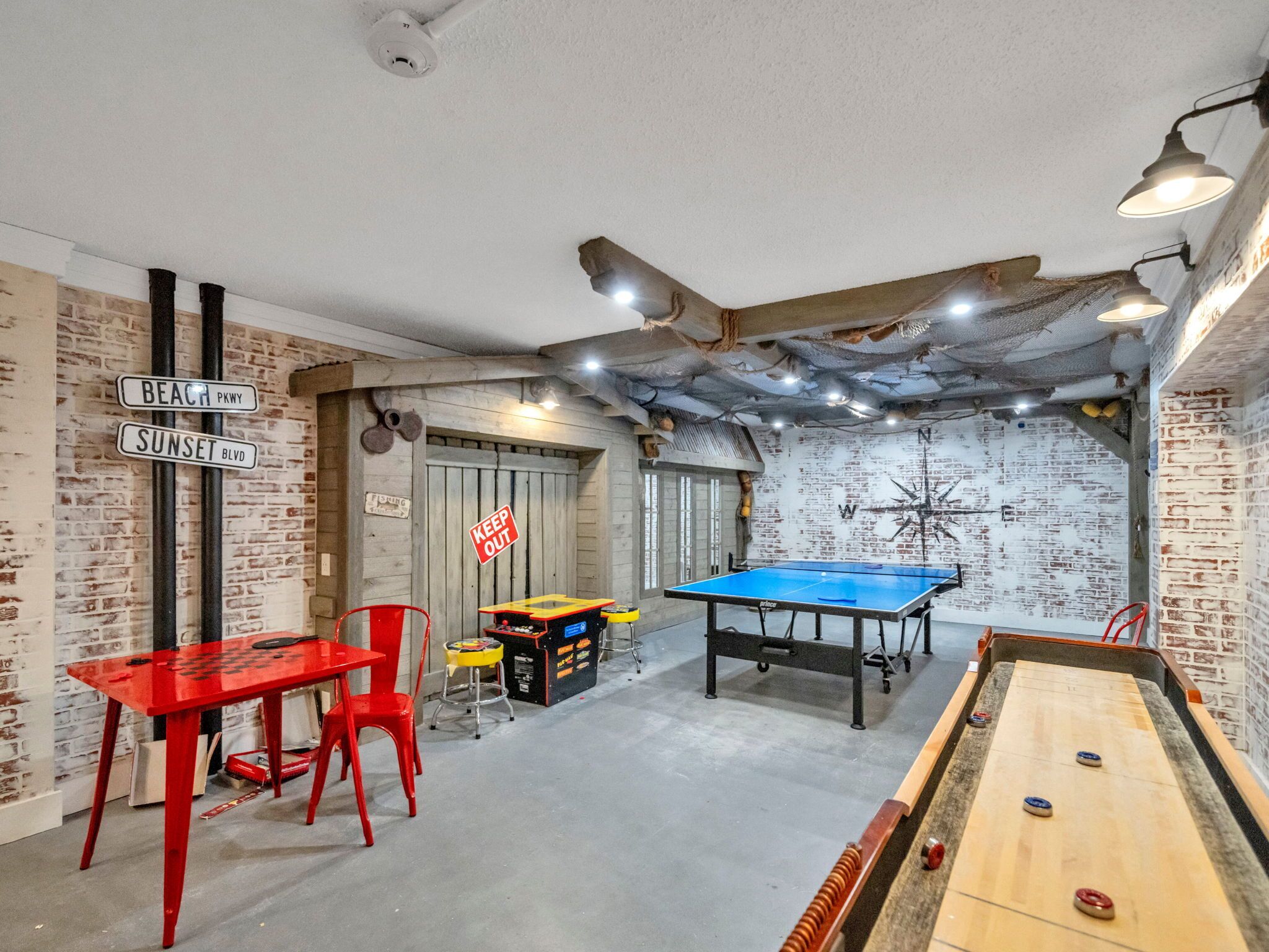 A room with a pool table, a red table with chairs, and a billiards table.