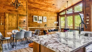 A wooden cabin interior with a kitchen, dining area, and large windows. - King beds, quiet neighborhood. Hot tub, games & fire pit! 5 mi to Dollywd.  (Sevierville)