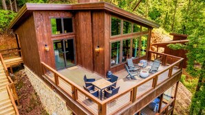 A two-story wooden cabin with a deck, large windows, and outdoor seating. - King beds, quiet neighborhood. Hot tub, games & fire pit! 5 mi to Dollywd.  (Sevierville)