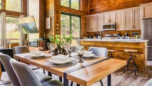 A wooden cabin interior with a dining area, kitchen, and large windows. - King beds, quiet neighborhood. Hot tub, games & fire pit! 5 mi to Dollywd.  (Sevierville)