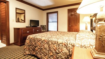 Un dormitorio con una cama grande, un aparador, un televisor y una ventana con persianas.