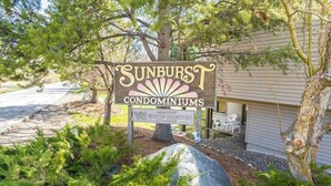 A sign for Sunburst Condominiums with a large rock and greenery in front. - Sunburst Condominiums (Steamboat Springs)