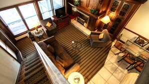 A spacious living area with a fireplace, comfortable seating, and a staircase leading to an upper level. - Sunburst Condominiums (Steamboat Springs)
