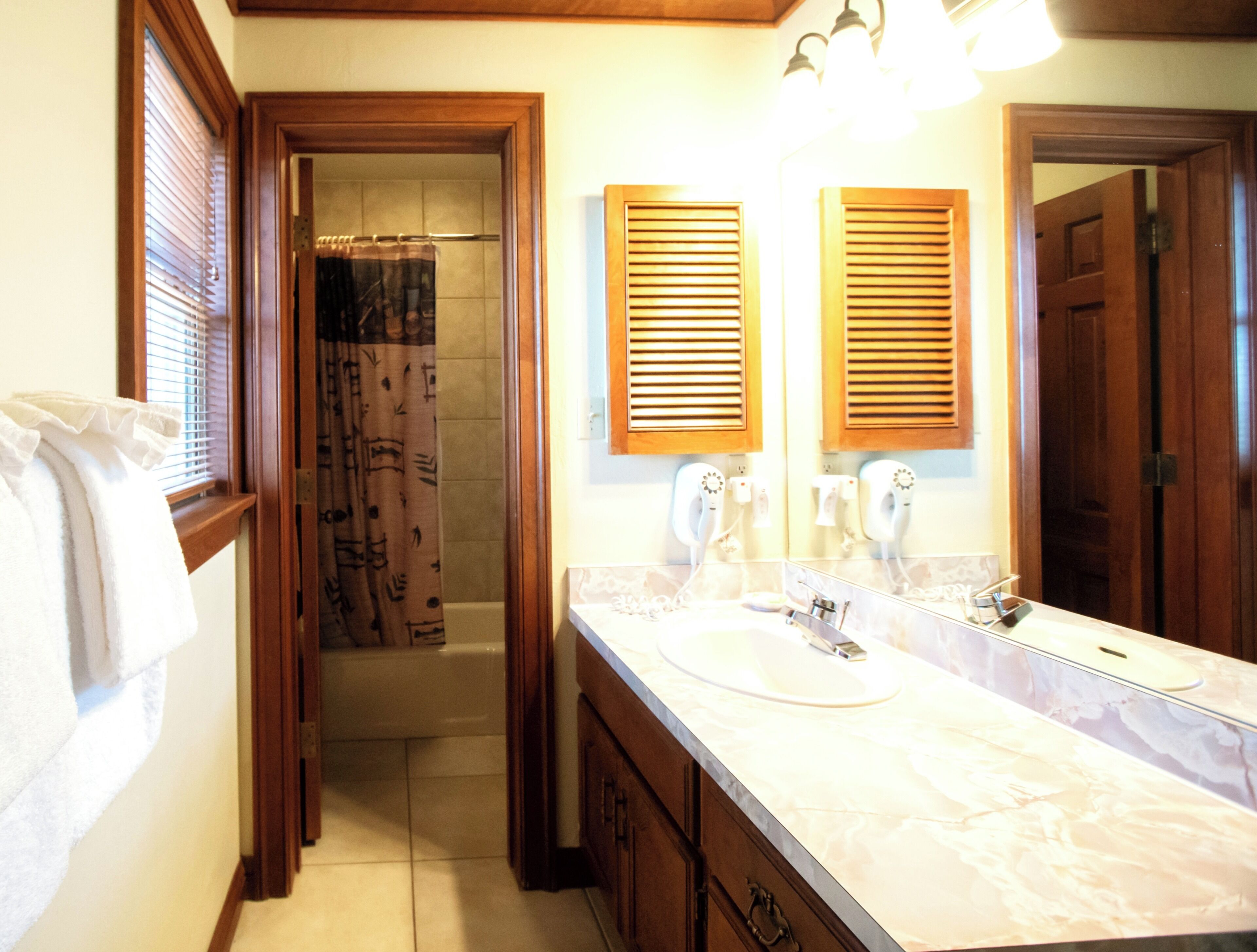 A bathroom with a sink, mirror, and shower.